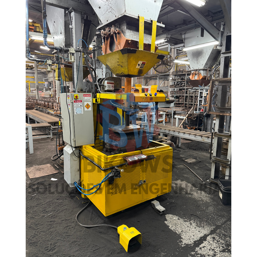 Prensa industrial de moldagem em fundição antes da automação, com painel de comando ao lado