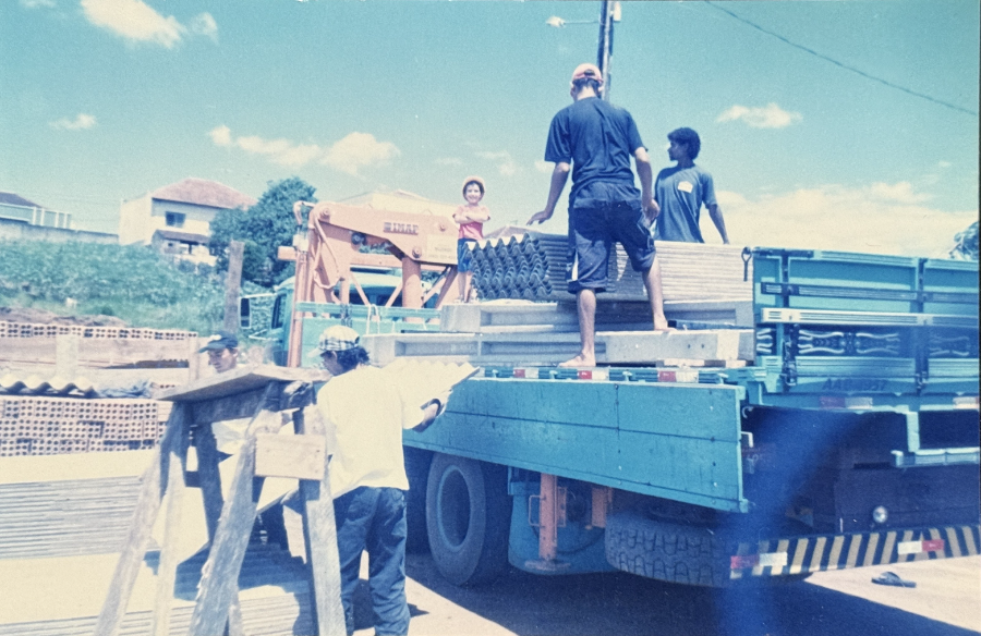 Marcos, ainda criança, e a equipe carregando materiais de estrutura metálica em caminhão da Bikows